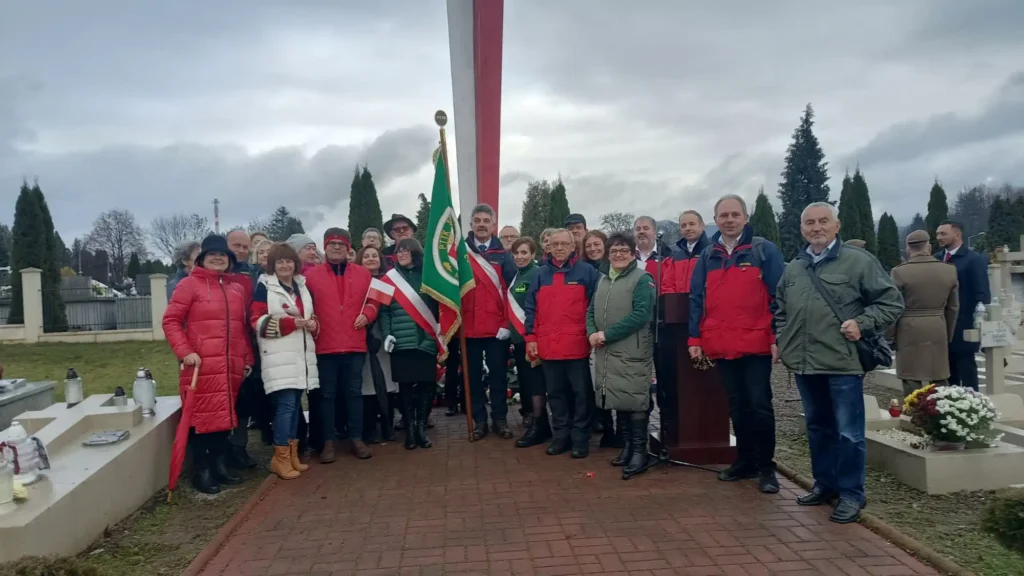 Członkowie PTTK Sanok z flagą organizacji podczas uroczystości patriotycznej przy pomniku – PTTK Ziemia Sanocka Święto Niepodległości