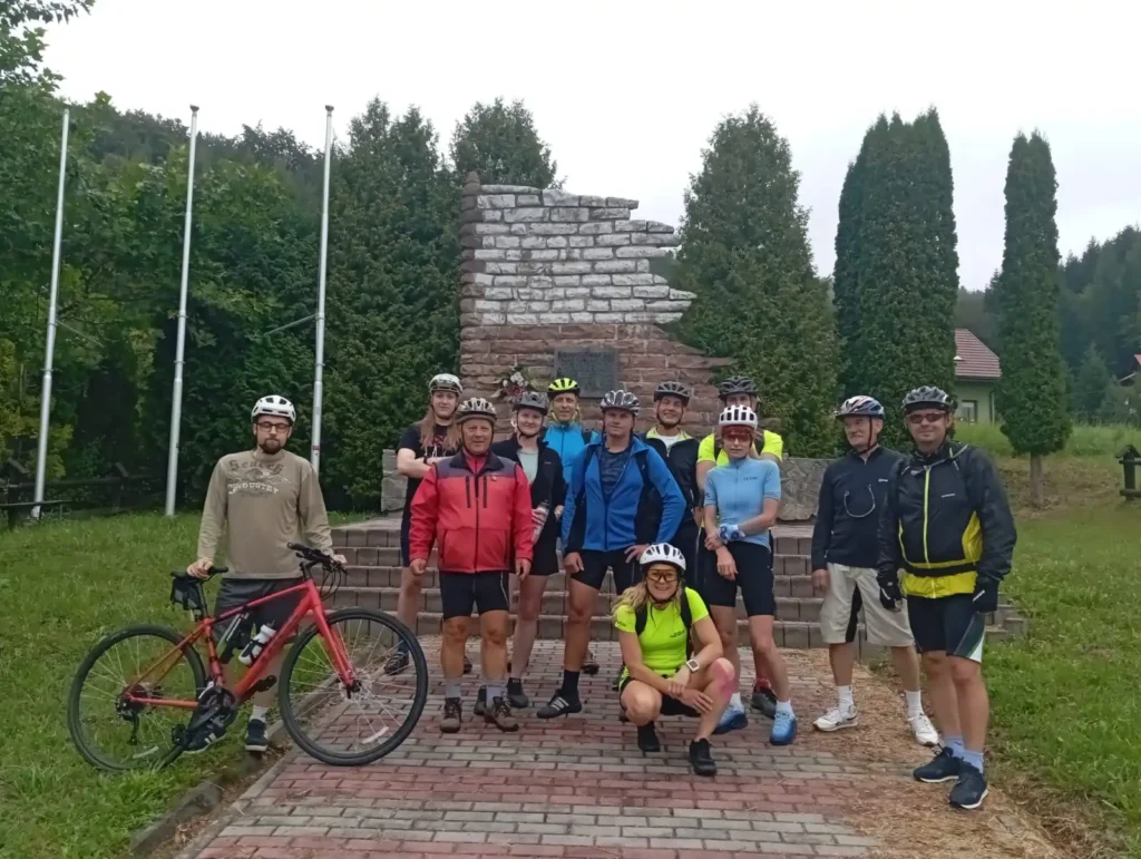 Grupa rowerzystów PTTK Sanok przy pomniku podczas rajdu rowerowego – rajd rowerowy PTTK Ziemia Sanocka