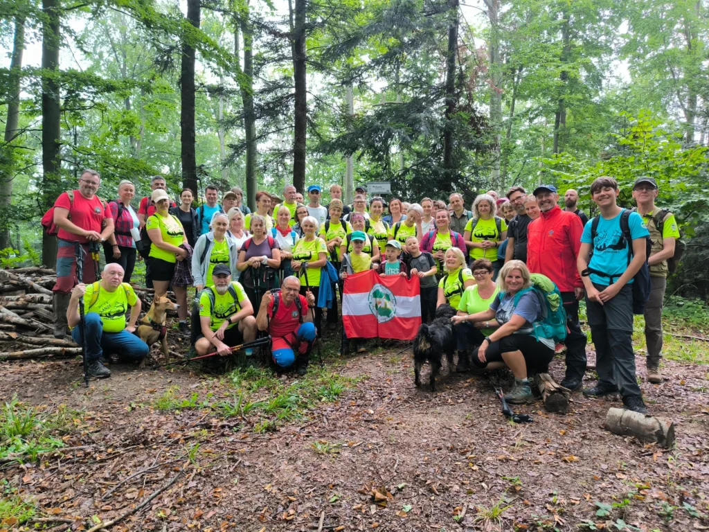Grupa turystów PTTK z flagą organizacji podczas wycieczki w lesie – PTTK Sanok turystyka leśna