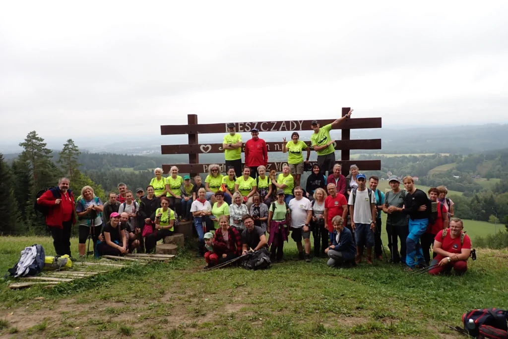 Turyści PTTK Sanok przy drewnianej tablicy Bieszczady podczas rajdu pieszego – rajd górski Bieszczady PTTK