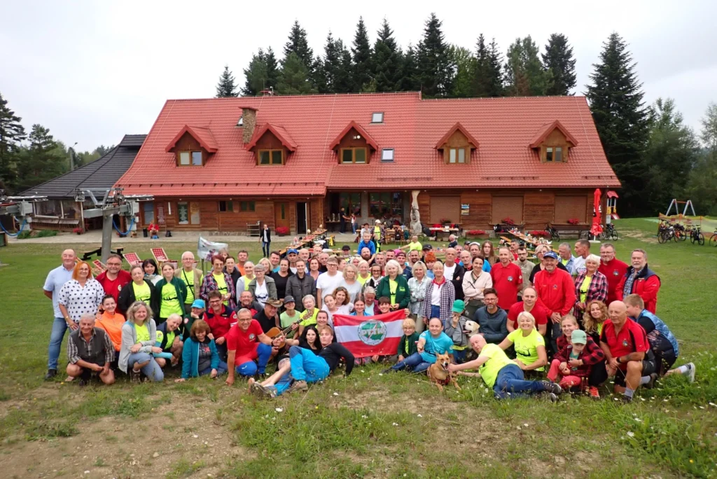 Uczestnicy imprezy turystycznej PTTK Sanok przy górskim schronisku z flagą organizacji – schronisko turystyczne Bieszczady